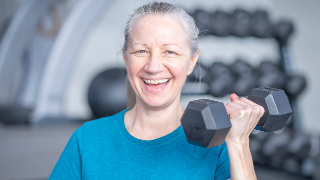 Woman with gray hair holding a dumbbell.